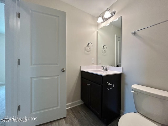 bathroom featuring hardwood / wood-style floors, toilet, and vanity with extensive cabinet space