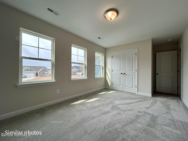 unfurnished bedroom with light colored carpet and a closet