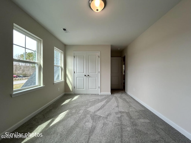 unfurnished bedroom featuring light carpet and a closet