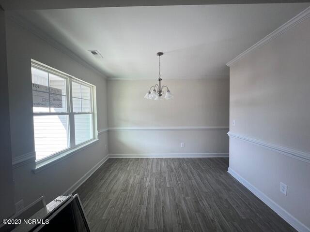 spare room with a notable chandelier, dark hardwood / wood-style floors, and ornamental molding