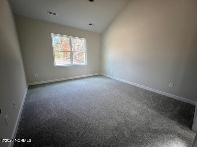 carpeted spare room featuring vaulted ceiling