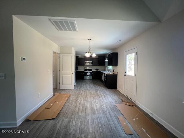 kitchen with an inviting chandelier, appliances with stainless steel finishes, dark wood-type flooring, and sink