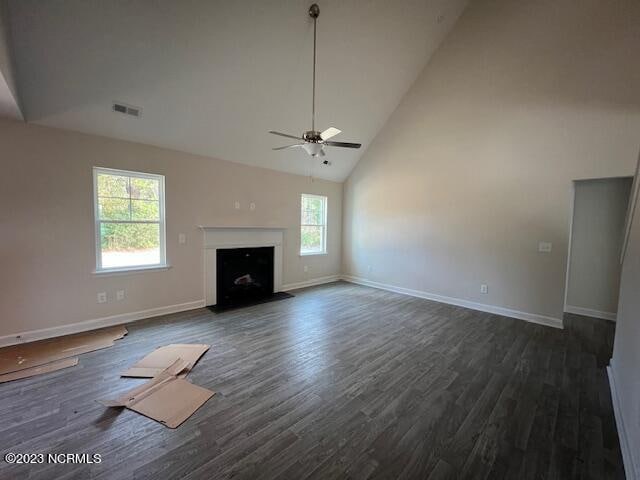 unfurnished living room with ceiling fan, dark wood-type flooring, and high vaulted ceiling