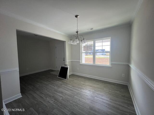 spare room with a chandelier, crown molding, and dark wood-type flooring