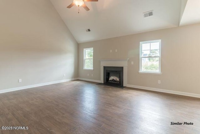 unfurnished living room featuring a healthy amount of sunlight, ceiling fan, and dark hardwood / wood-style flooring