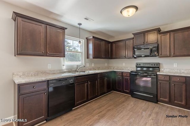 kitchen with dark brown cabinets, light hardwood / wood-style flooring, black appliances, pendant lighting, and sink