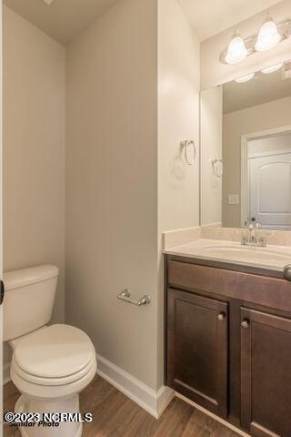 bathroom with hardwood / wood-style floors, toilet, and vanity