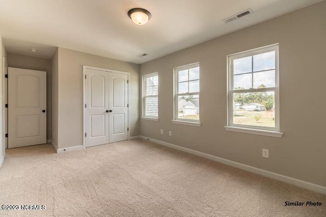 unfurnished bedroom featuring light carpet and a closet