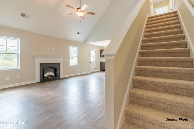 stairs featuring ceiling fan, high vaulted ceiling, and light wood-type flooring