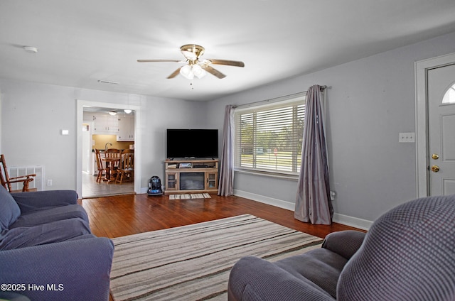 living area with baseboards, ceiling fan, visible vents, and wood finished floors