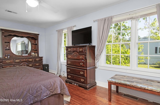 bedroom featuring visible vents, baseboards, ceiling fan, and wood finished floors