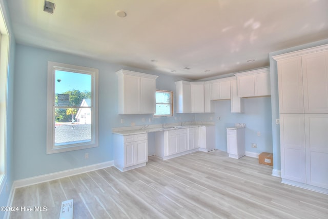 kitchen featuring white cabinetry, light hardwood / wood-style flooring, a healthy amount of sunlight, and sink