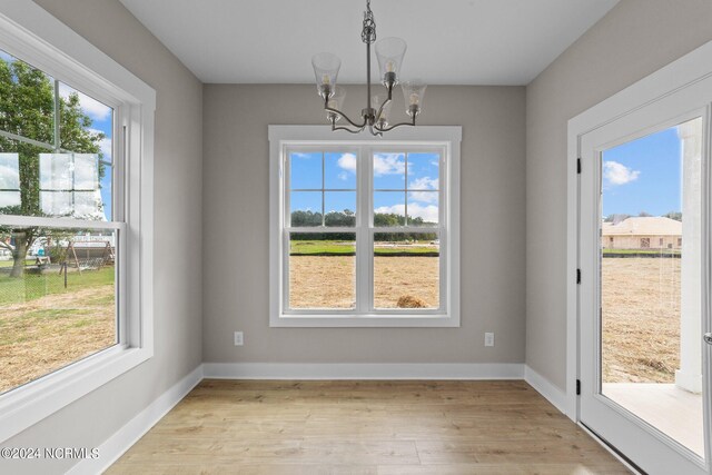 unfurnished dining area featuring a notable chandelier and light hardwood / wood-style floors