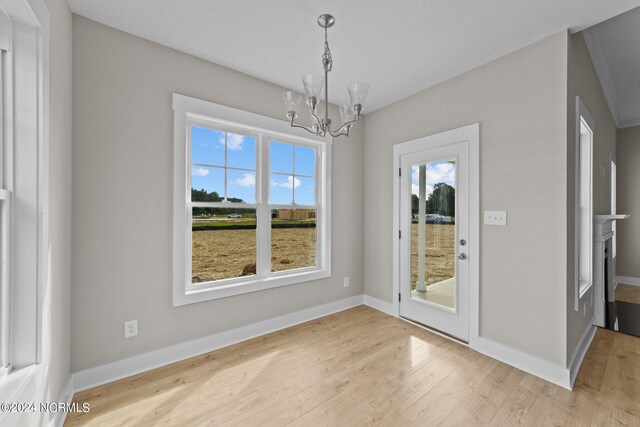 unfurnished dining area featuring an inviting chandelier and light hardwood / wood-style floors