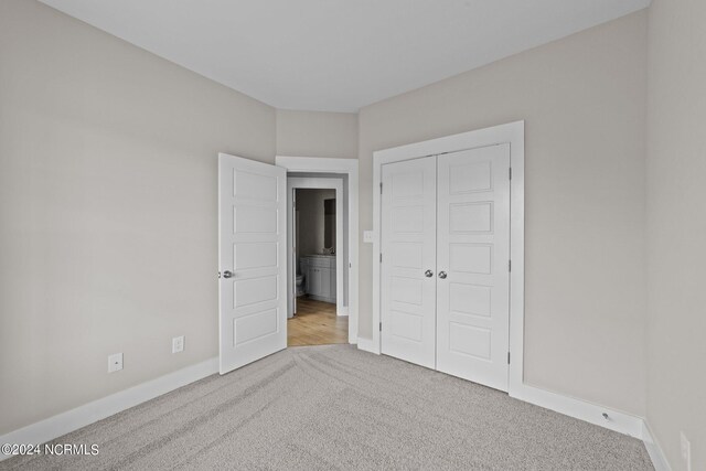 unfurnished bedroom with light colored carpet and a closet