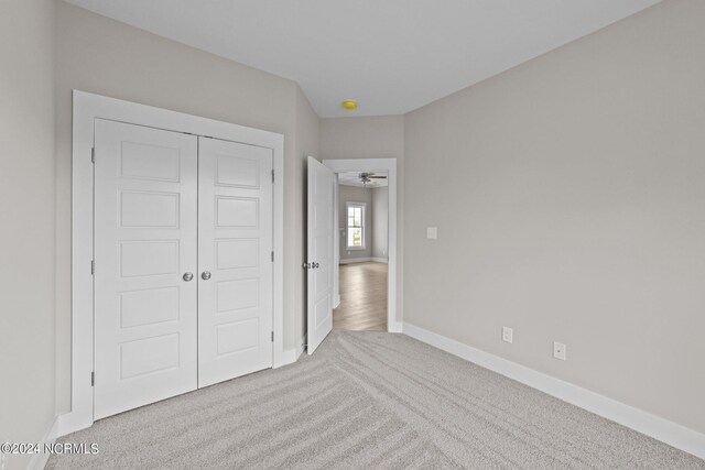 unfurnished bedroom with light carpet and a closet