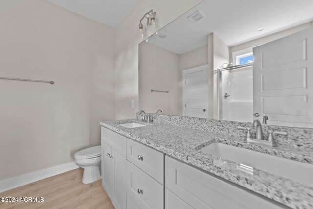 bathroom with walk in shower, vanity, hardwood / wood-style floors, and toilet