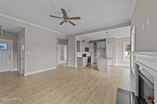 unfurnished living room featuring light wood-type flooring, crown molding, sink, and ceiling fan