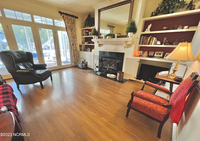 living room with built in features, ornamental molding, and light hardwood / wood-style flooring