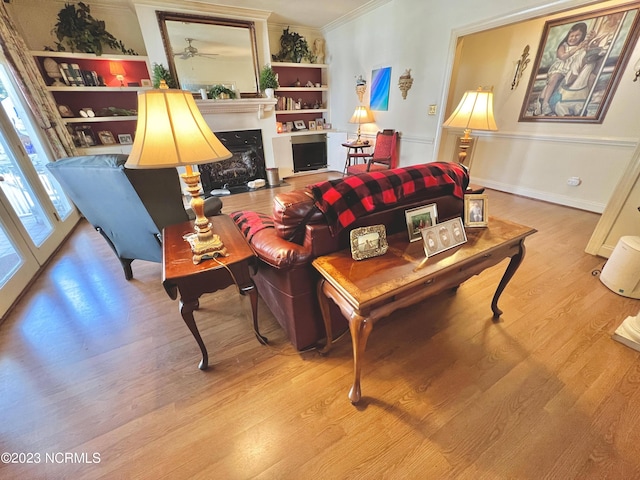 living room featuring ornamental molding, light wood-type flooring, and french doors