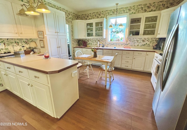 kitchen with hanging light fixtures, wood-type flooring, and stainless steel fridge