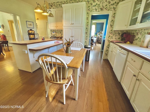 dining space featuring crown molding, light wood-type flooring, and decorative columns