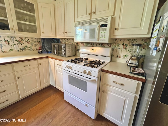 kitchen with light hardwood / wood-style flooring, white appliances, and white cabinets