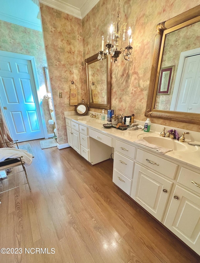 bathroom featuring double vanity, ornamental molding, a notable chandelier, and wood-type flooring