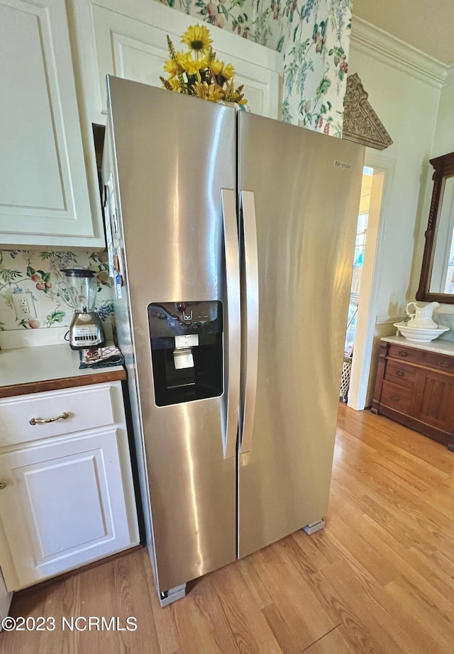 kitchen with white cabinets, stainless steel fridge with ice dispenser, light hardwood / wood-style floors, and crown molding