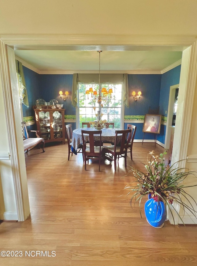 dining space featuring an inviting chandelier, ornamental molding, and light wood-type flooring