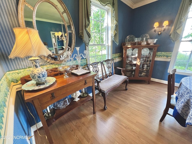 interior space featuring a notable chandelier, multiple windows, light hardwood / wood-style flooring, and ornamental molding