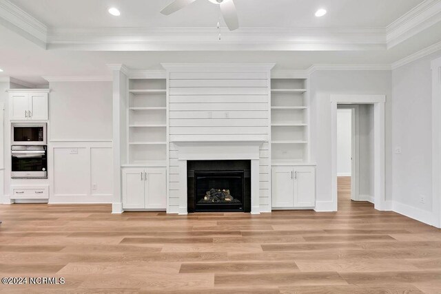 unfurnished living room featuring a tray ceiling, ceiling fan, light hardwood / wood-style floors, and ornamental molding