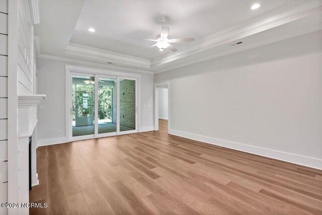 unfurnished living room featuring light hardwood / wood-style flooring, a tray ceiling, ornamental molding, and ceiling fan