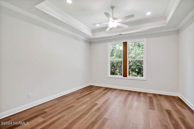 unfurnished room featuring a tray ceiling, crown molding, wood-type flooring, and ceiling fan