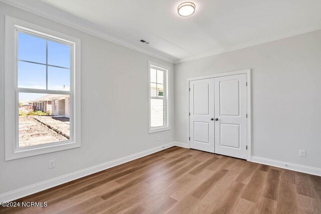 empty room with crown molding and wood-type flooring