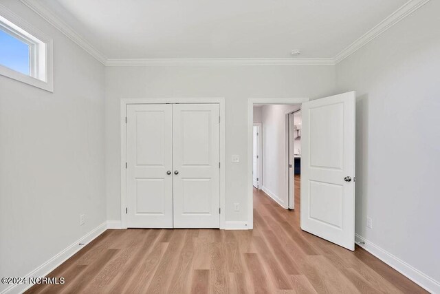 unfurnished bedroom with light wood-type flooring, a closet, and ornamental molding