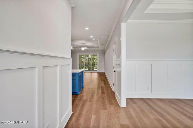 corridor with ornamental molding and light hardwood / wood-style flooring