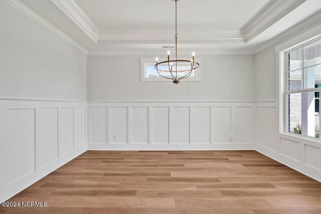 unfurnished dining area featuring light wood-type flooring, plenty of natural light, an inviting chandelier, and crown molding