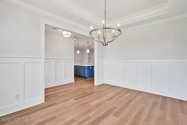 unfurnished dining area featuring ornamental molding, light wood-type flooring, an inviting chandelier, and sink