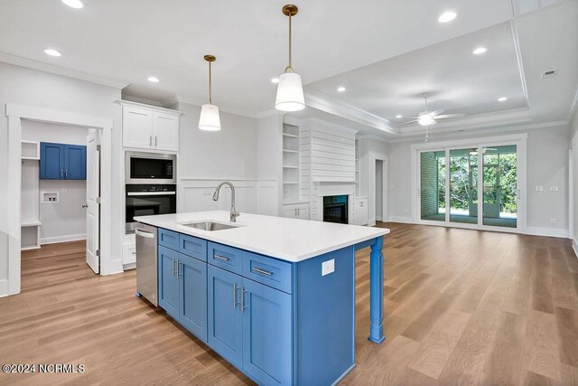 kitchen featuring a raised ceiling, blue cabinets, light hardwood / wood-style flooring, stainless steel appliances, and ceiling fan