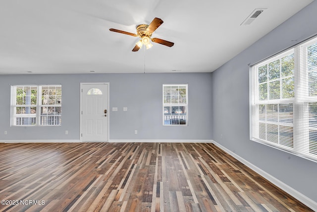 unfurnished room with ceiling fan, dark wood-type flooring, and a healthy amount of sunlight