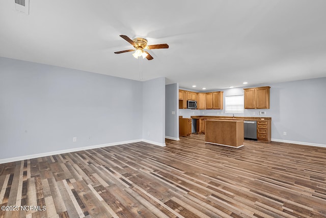 unfurnished living room featuring dark wood-type flooring and ceiling fan