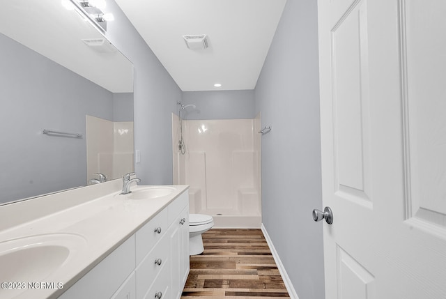 bathroom with dual bowl vanity, a shower, toilet, and hardwood / wood-style floors