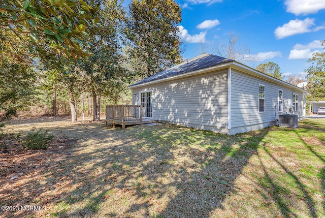 view of property exterior featuring central AC unit, a wooden deck, and a lawn