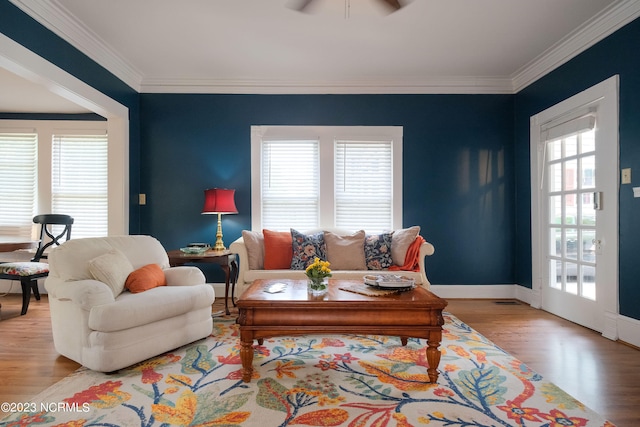 living area featuring baseboards, ceiling fan, wood finished floors, and crown molding