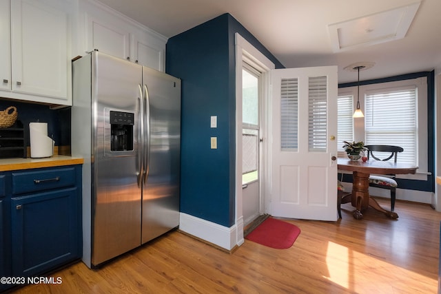 kitchen with plenty of natural light, blue cabinetry, stainless steel fridge with ice dispenser, and light wood finished floors