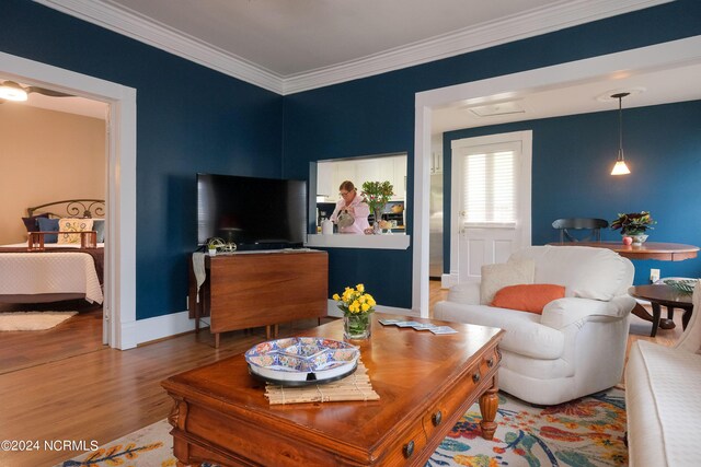 living area with ornamental molding, baseboards, and wood finished floors