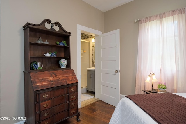 bedroom featuring ensuite bath and dark wood-style flooring