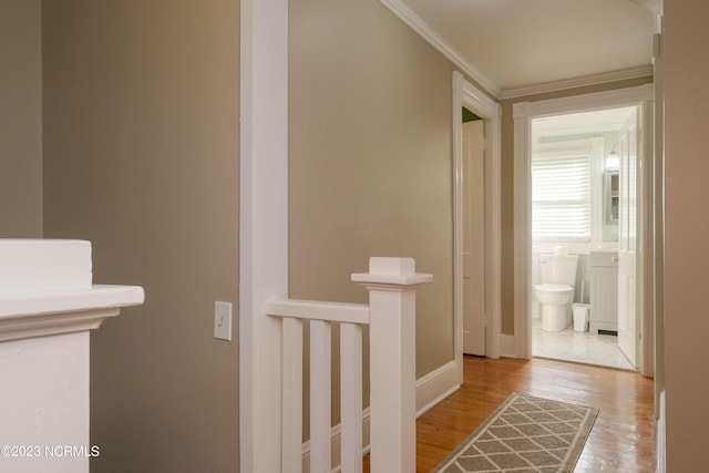 hall featuring baseboards, light wood finished floors, and crown molding