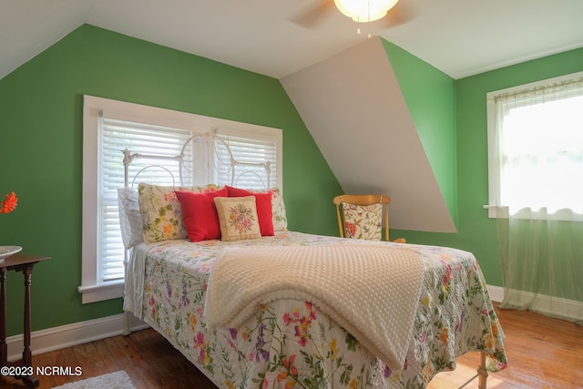 bedroom featuring multiple windows, vaulted ceiling, and wood finished floors